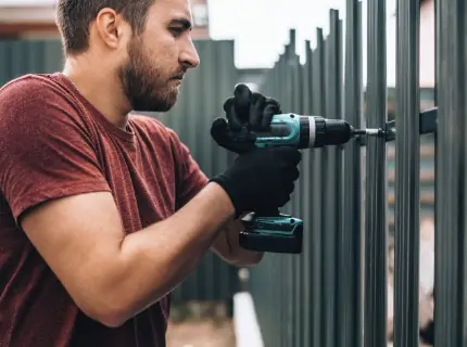 Man installing a metal fence.