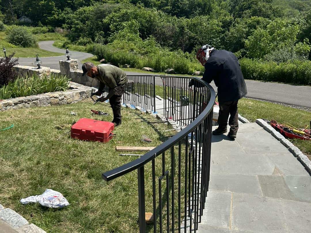 Two iron workers assembling the stair railing.