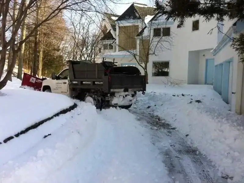 Plow truck clearing a residential driveway in western Connecticut, with snow piled along the edges